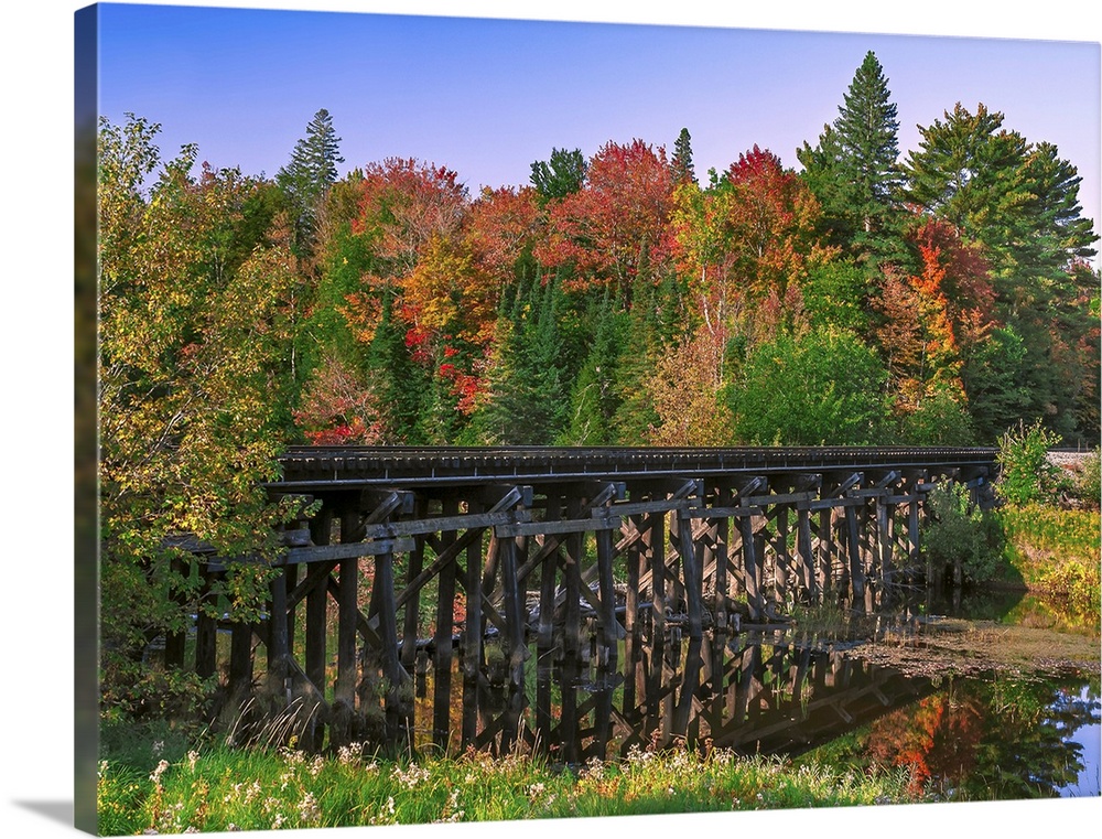 A wooden trestle railroad bridge over a  river in a Michigan forest, with trees changing to fall colors.