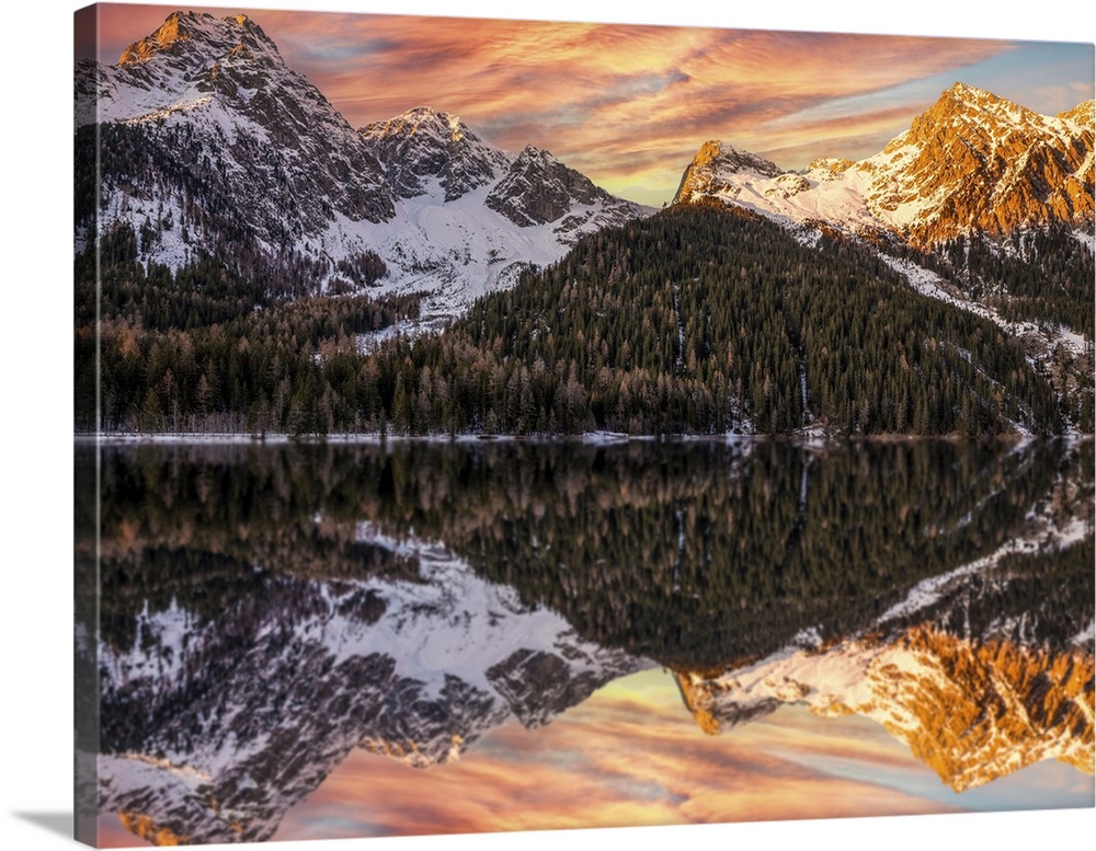 An alpine landscape in the middle of Lake Anterselva after a heavy snowfall. The sunset with its warm colors color the pea...