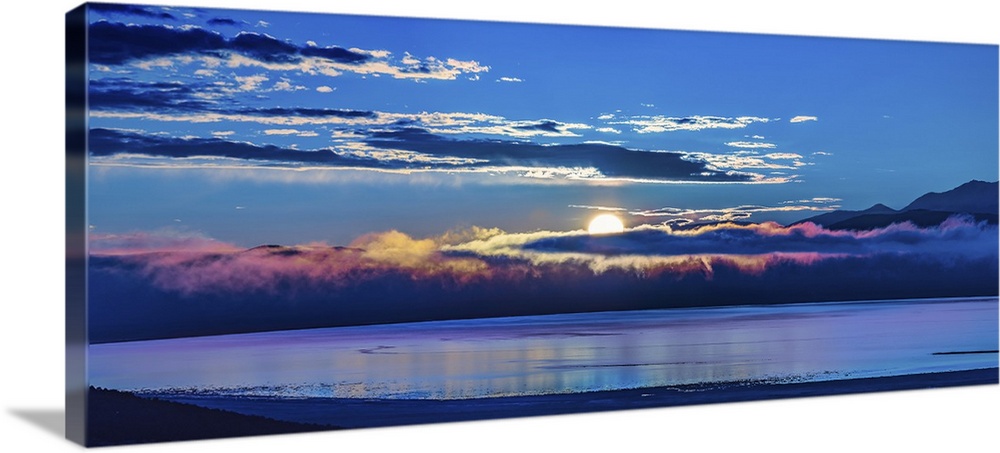 The sun peeking behind the clouds at dawn over Mono Lake, California.