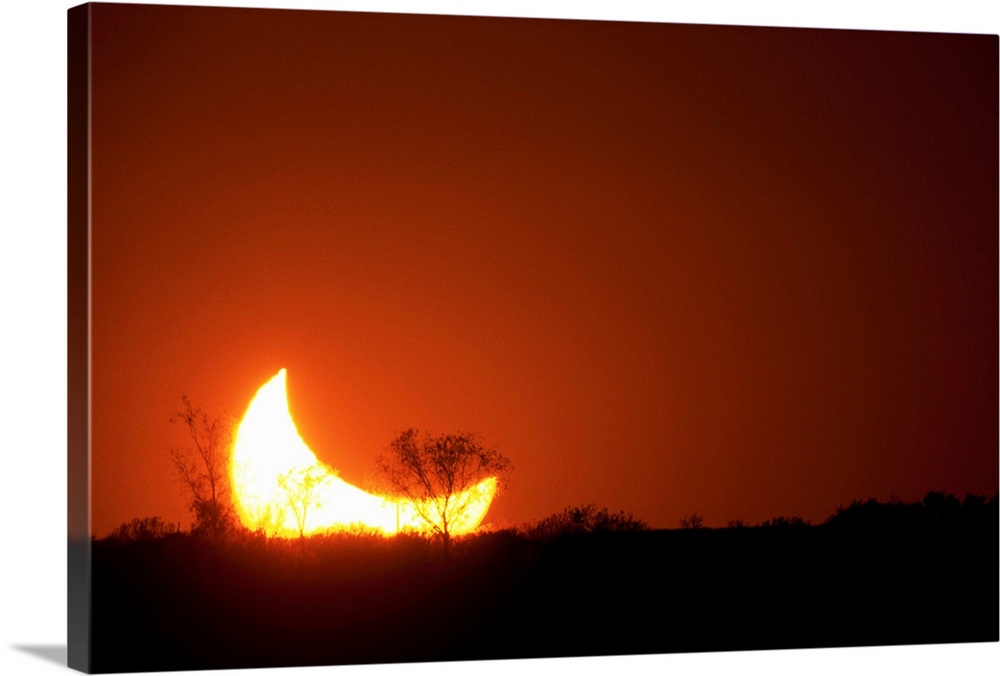 Sun and moon set in a partial eclipse on horizon