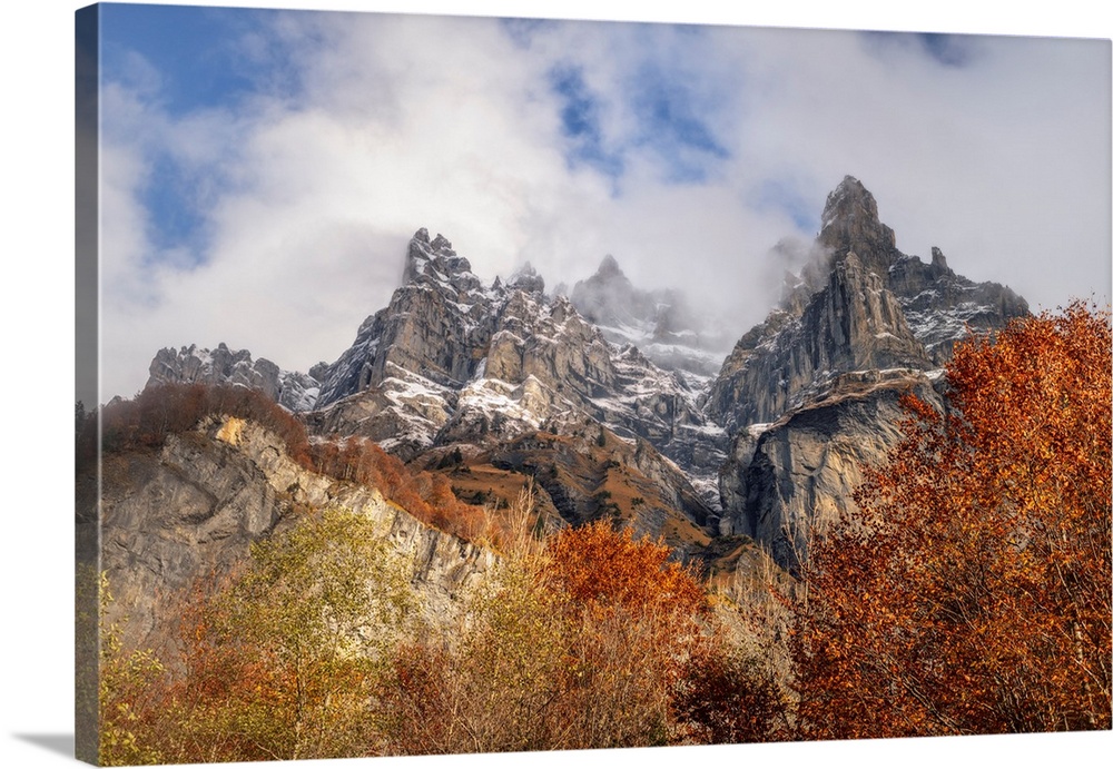 Place of Sixt-Fer-a-Cheval area in Savoie, France, big colored orange and yellow mountains at fall with white clouds under...