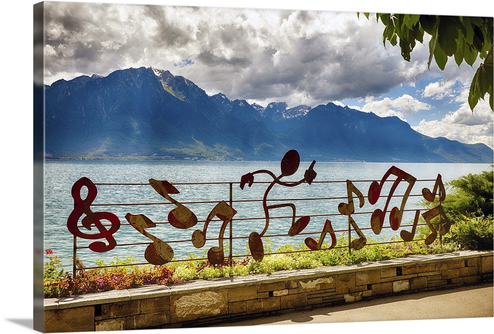 A photograph of a mountain range in the distance from musical notation decorated fence.