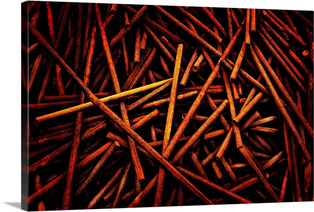 A pile of wooden dowels is photographed artistically with some slightly lighter than others.