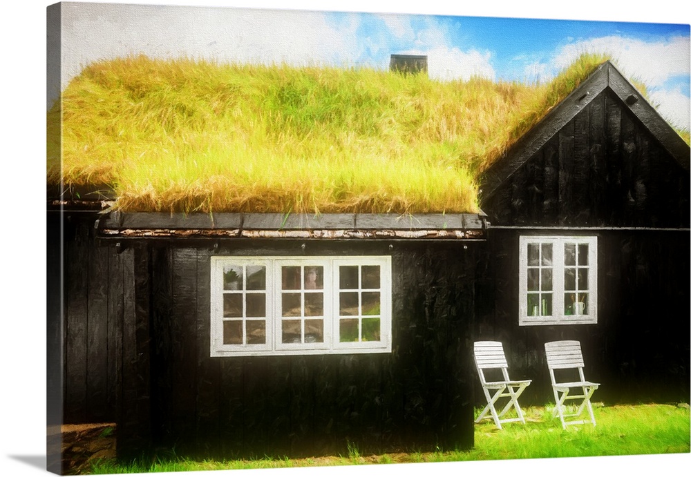 A black house with white framed windows and a grassy roof.