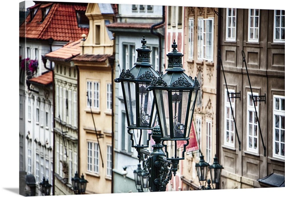 A pair of historic gas lamps by buildings in the city of Prague.