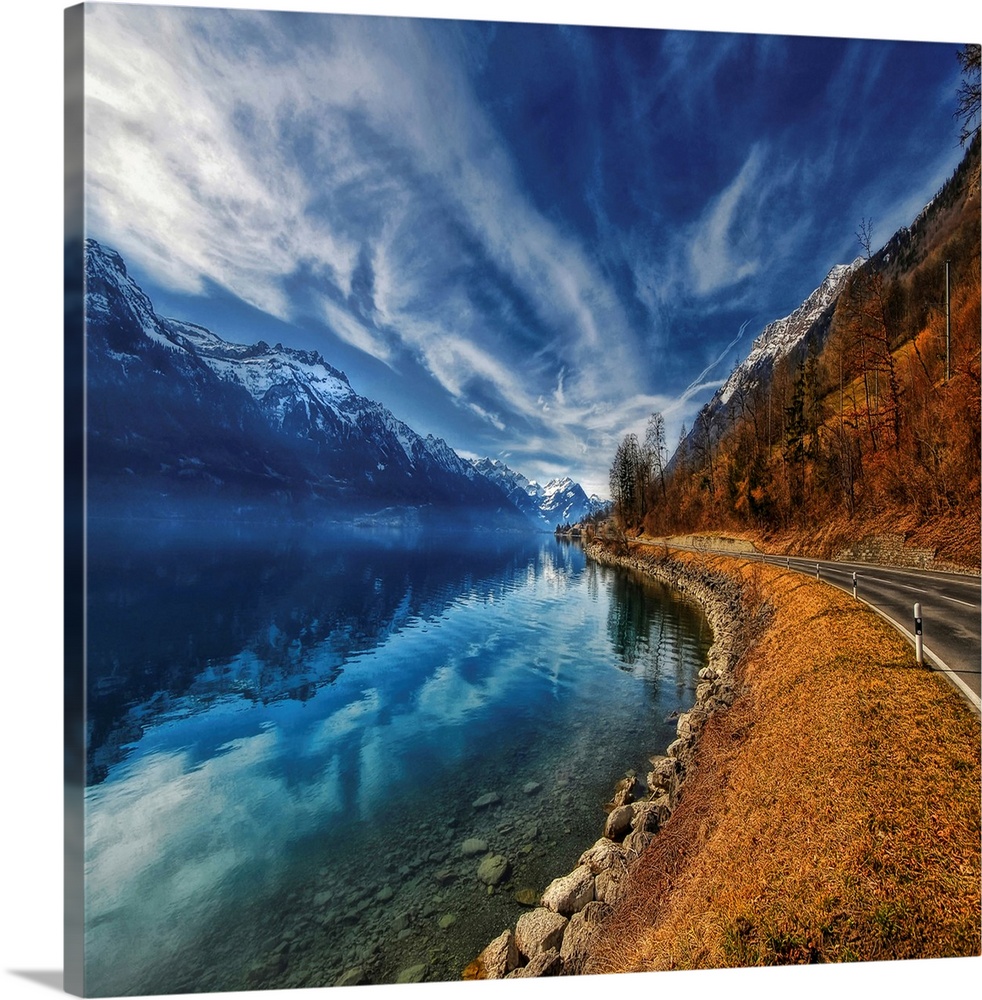 This oversize piece is a picture taken of a winding road with a breathtaking view of mountains on the left that reflect in...
