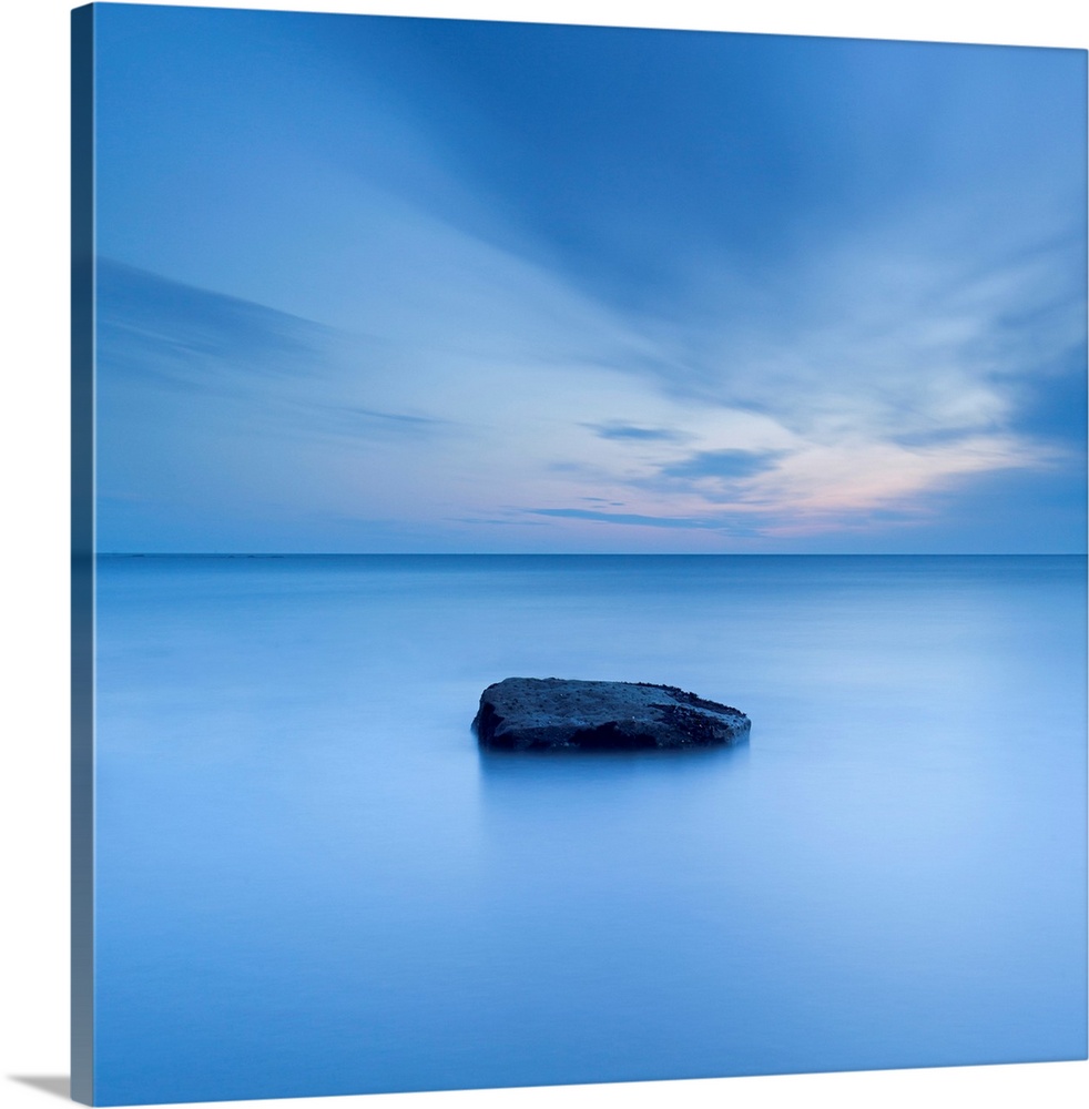 A zen calm minimal minimalist cool deep blue image of one rock in a flat calm sea.