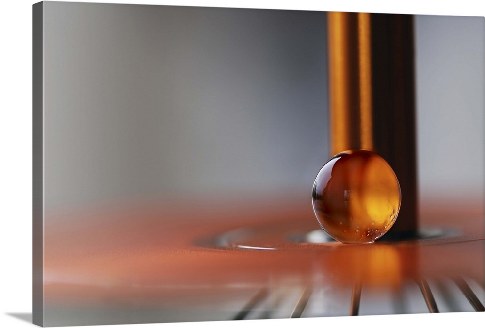 A macro photograph of an orange water droplet against a abstract background.