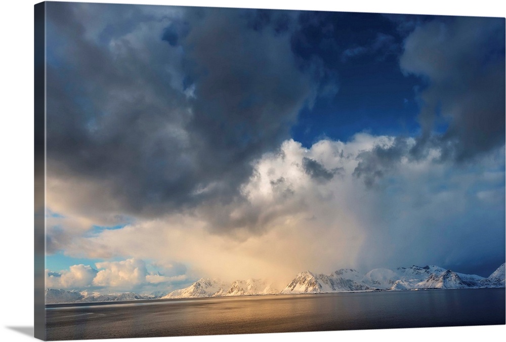 A mountain range seen far in the distance across a fjord under a sky filled with ornate clouds.