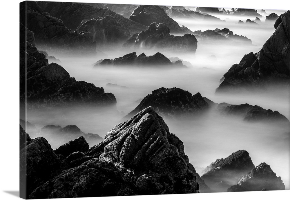 Rocky outcroppings rising above the mist on the coast in Point Lobos, California.