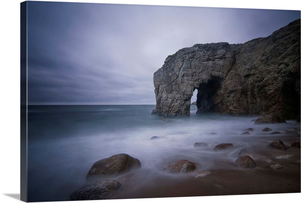 He natural arch rock in Quiberon island in Britany at high tide, a long colored time exposure, sand beach in France on the...