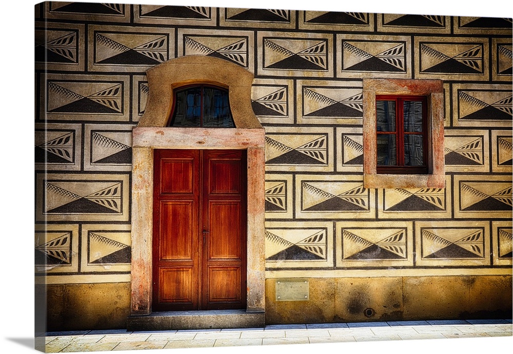 Decorative panels around a window and door on the facade of a building in Prague.