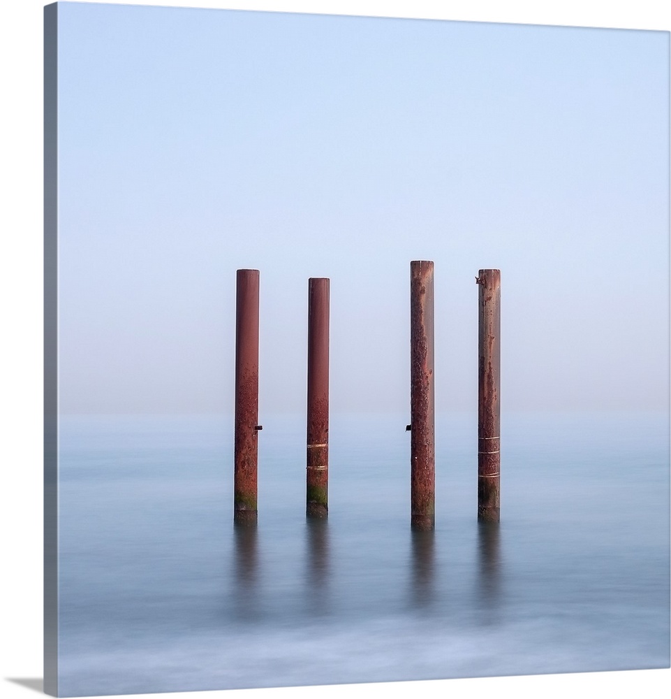 Four wooden posts standing in flowing water.