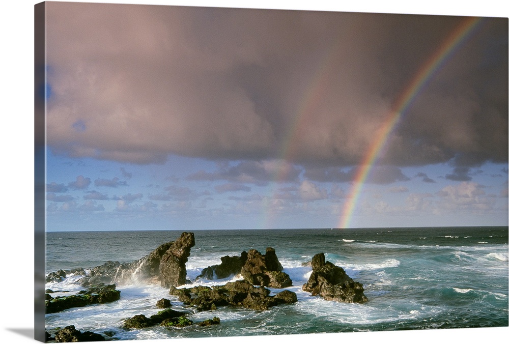 A rare double-rainbow arches across the rocky shore after a storm in a coastal landscape, Maui, Hawaii