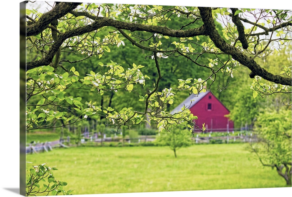 A photograph of a countryside scene with a red barn seen in the distance.