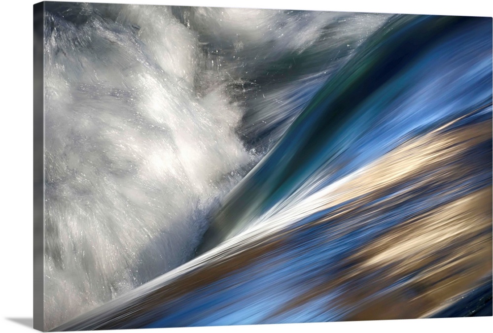 Abstract photo of rushing water with color reflecting off the waves.