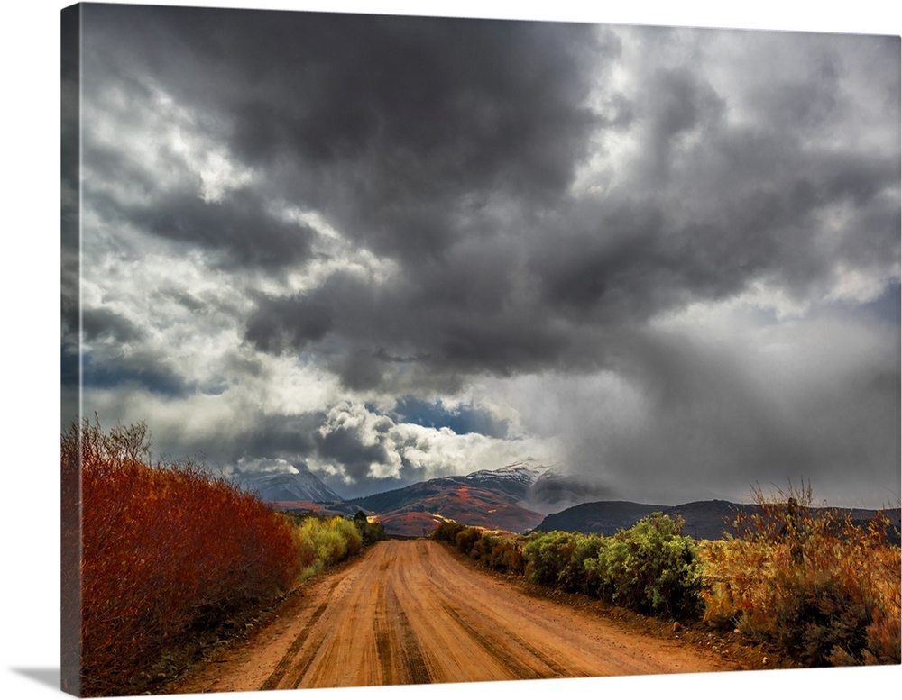 Dark storm clouds over a dirt road in the countryside.