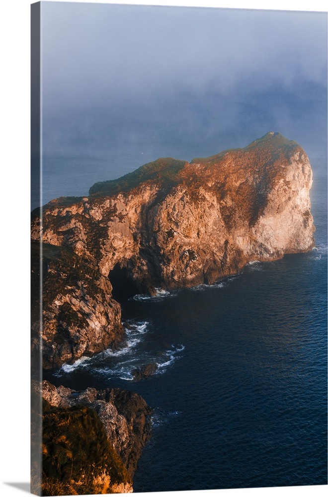 Rocky cliffs in the fog near Kinbane Castle in Northern Ireland during a winter sunrise.