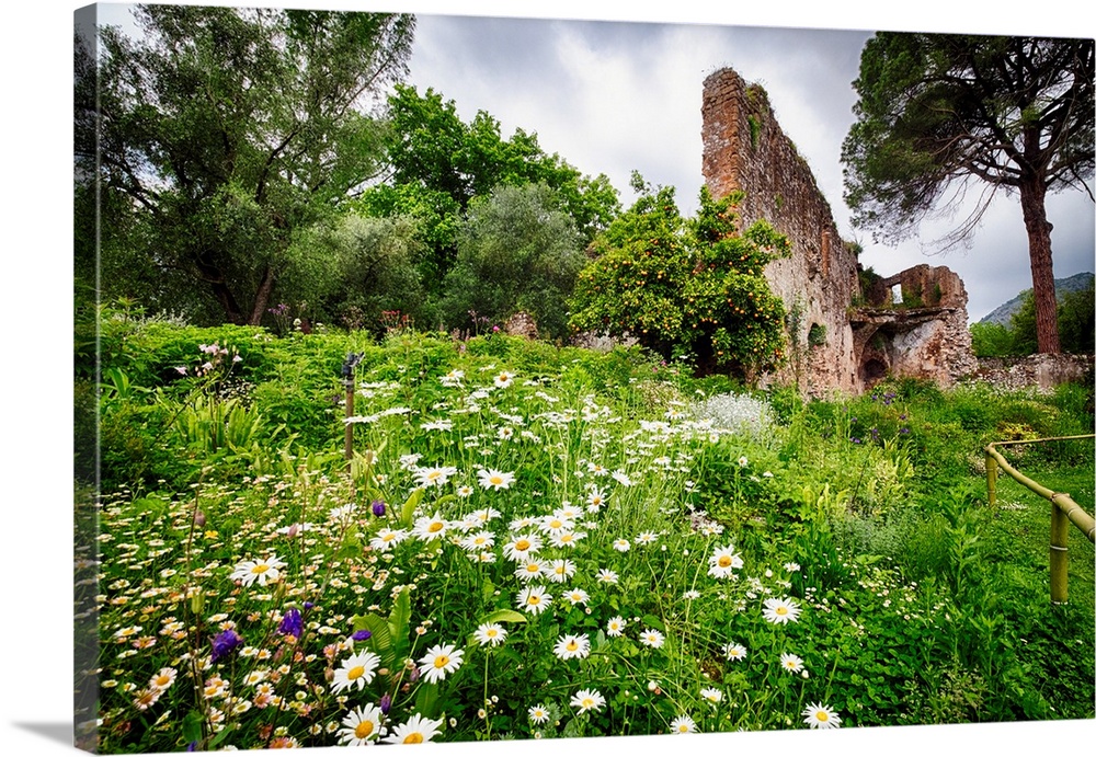 Ruins in a garden with flowers and orange tree, Garden of Ninfa, Cisterna di Latina, Italy.