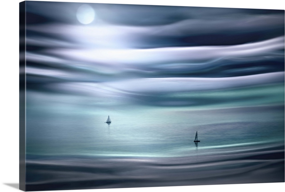 Dreamy photograph in shades of blue of the ocean with two sailboats sailing in the moonlight with rippled waves below and ...