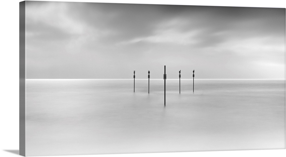 Minimal panoramic monochrome black and white zen calm seascape with five poles in the flat sea.