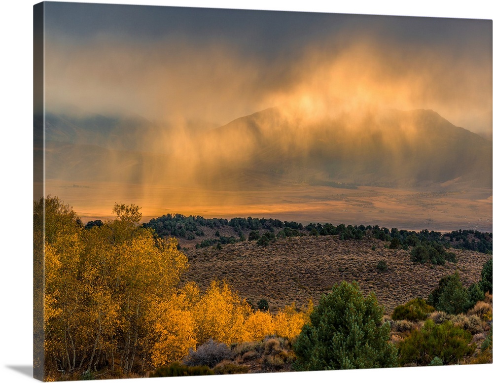 Rainclouds lit up with sunlight over the Sierra Nevada landscape.