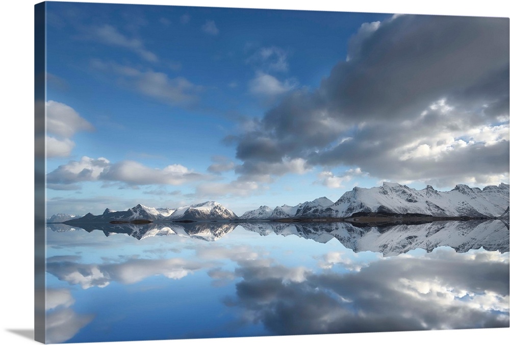 Photograph of a still lake casting a snow covered mountain and cloud reflection.