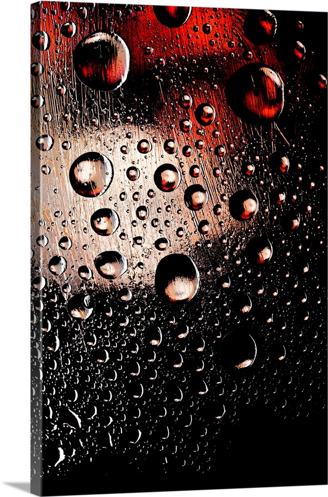 A photo of raindrops sitting on a window with red and white lights shining behind.