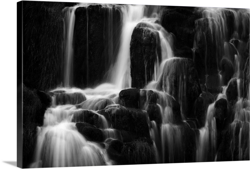Fine art photo of a waterfall over several round rocks in black and white.