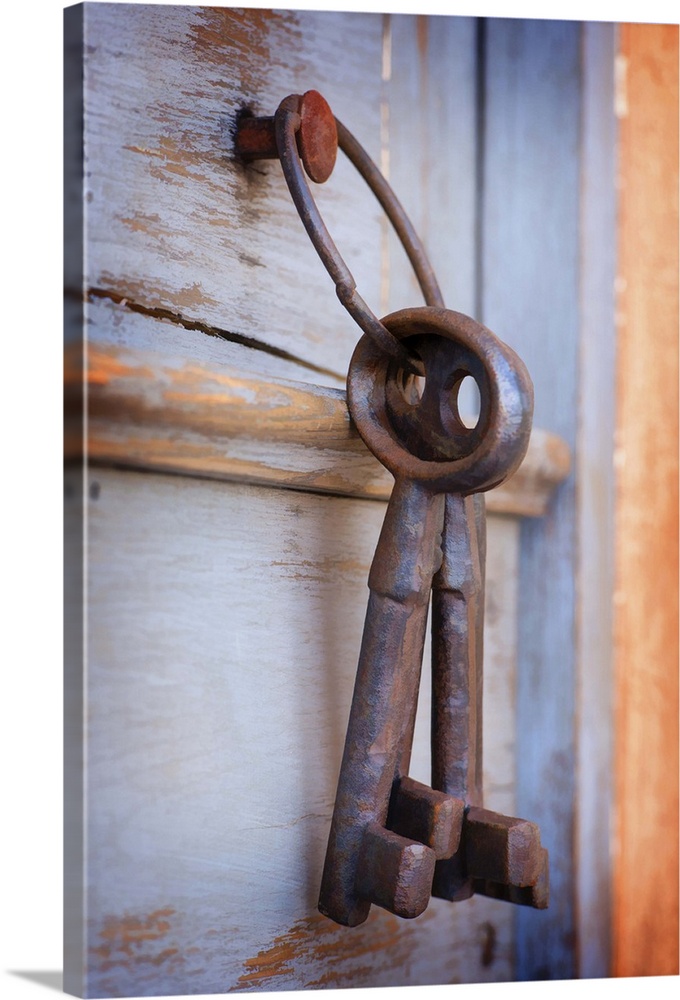 A photograph of a set of large rustic keys hanging on a wooden door.