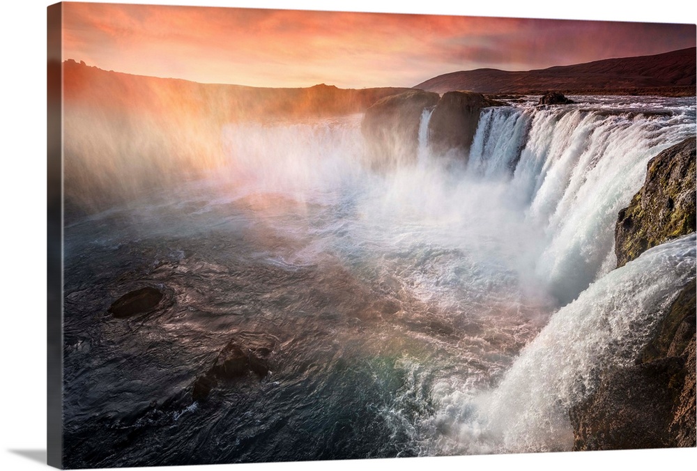 Fine art photograph of a large series of waterfalls with orange sunlight shining down.