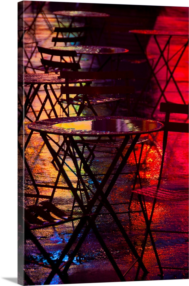 Red and orange light shining on the wet surfaces of tables outside of Times Square, New York.