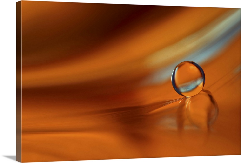 A macro photograph of a water droplet sitting on an orange surface.