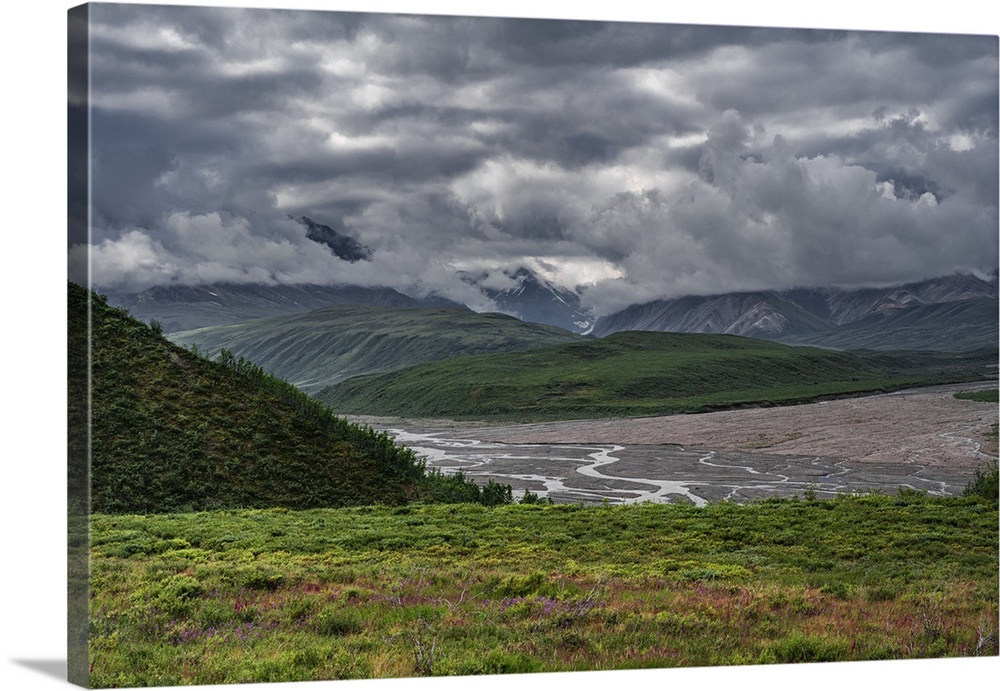 Multiple terrain features grace this beautiful Alaskan landscape with colorful foliage forground, tree-dappled hills, stre...