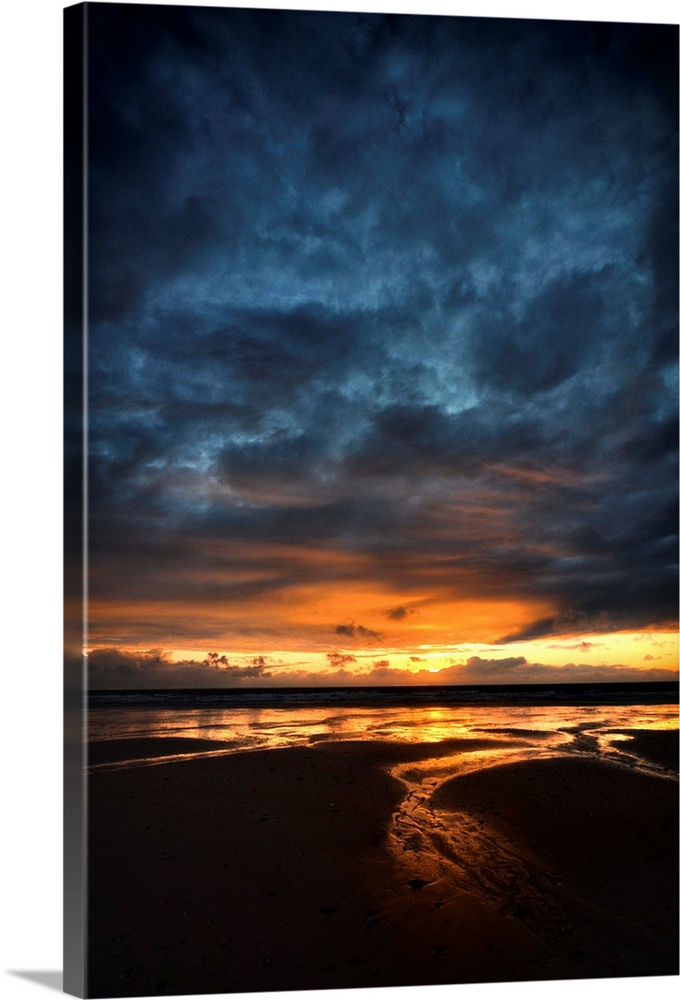 Sunrise with orange and blue colors on a sand beach in France, vertical view.