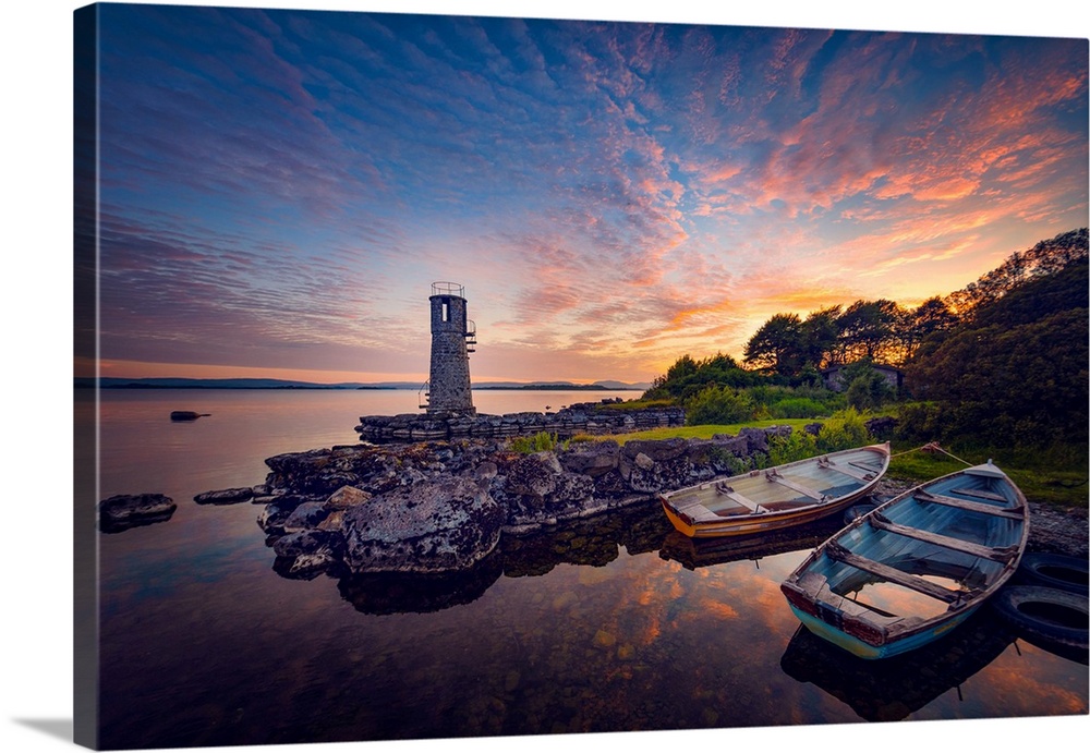 Sunset in Ireland with rowing boats in the foreground around a lighthouse