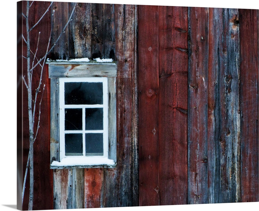 White window on the side of a weathered red barn.