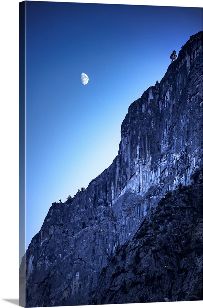 The moon in the sky over the side of a mountain in Yosemite National Park, California.