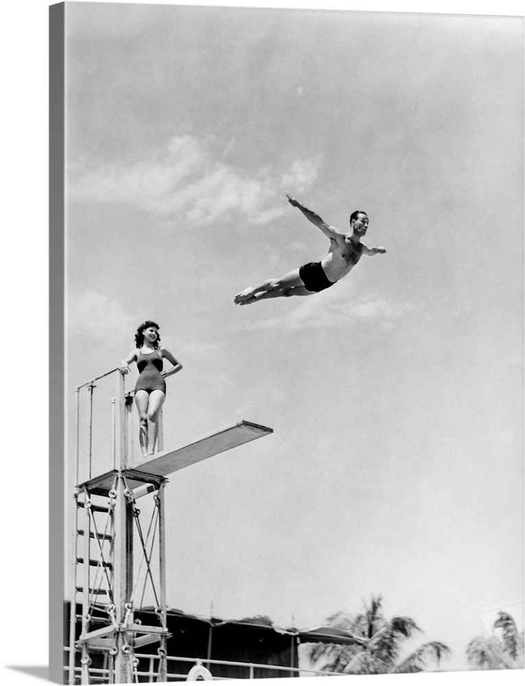 1930s 1940s Shapely Woman Watching Man Swan Dive Off High Diving Board.