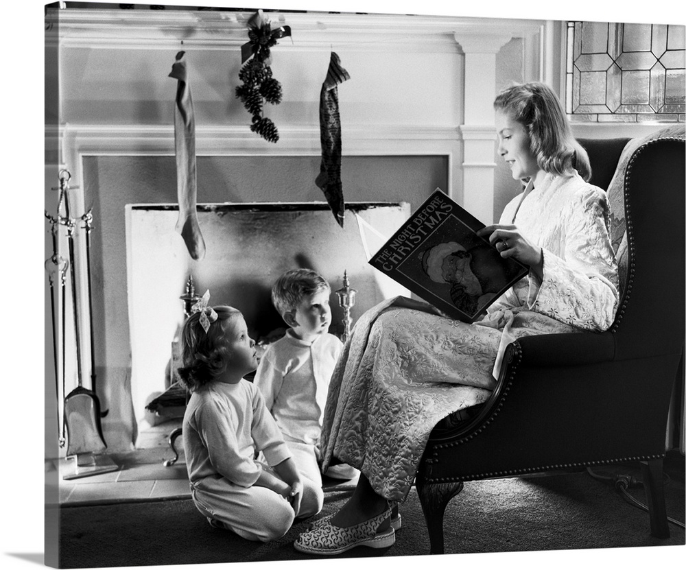 1940s 1950s Mother Reading Christmas Story To Boy Girl Sitting By Fireplace Hung With Stockings.
