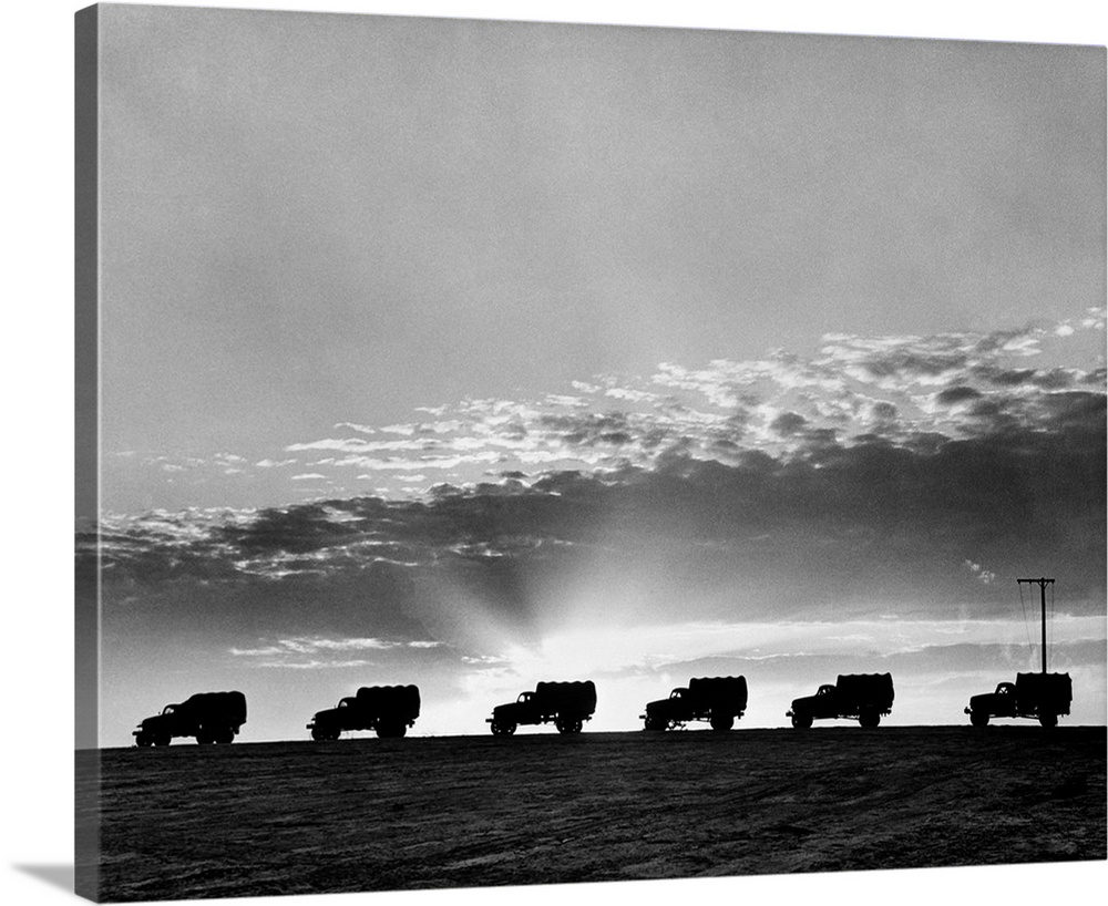 1940's Line Of Anonymous Silhouetted Military Army Trucks In Convoy At Sunrise Or Sunset.