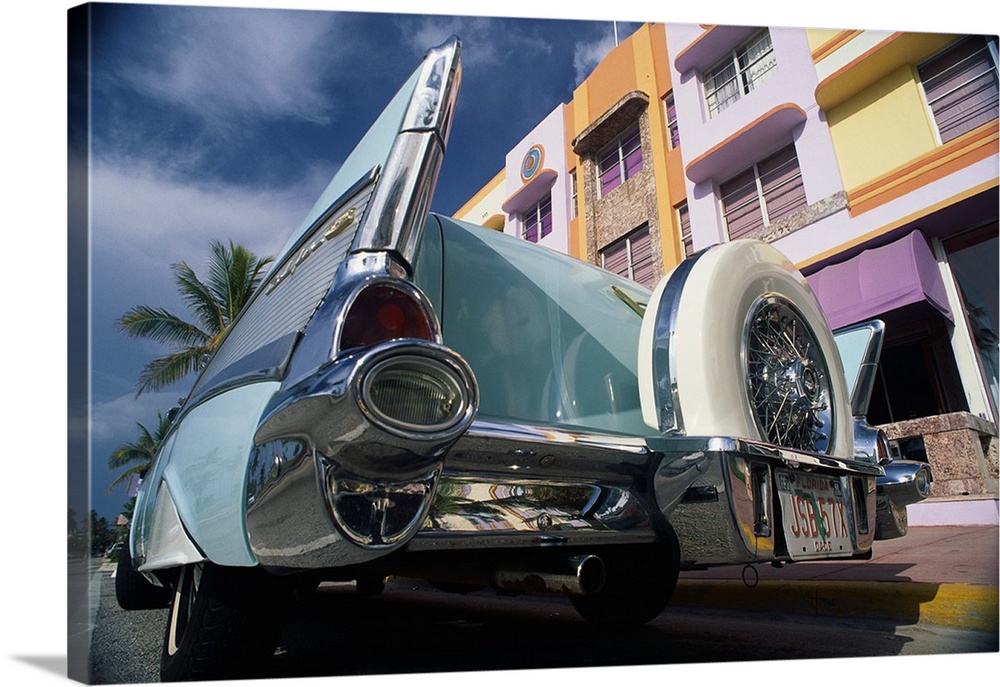 Up-close photograph of classic car from behind on street lined with colorful buildings.