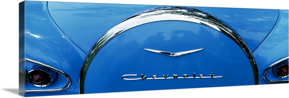 Oversized, landscape photograph of the back end of a shiny blue 1958 Chevrolet Bel-Air, including part of the trunk and ta...