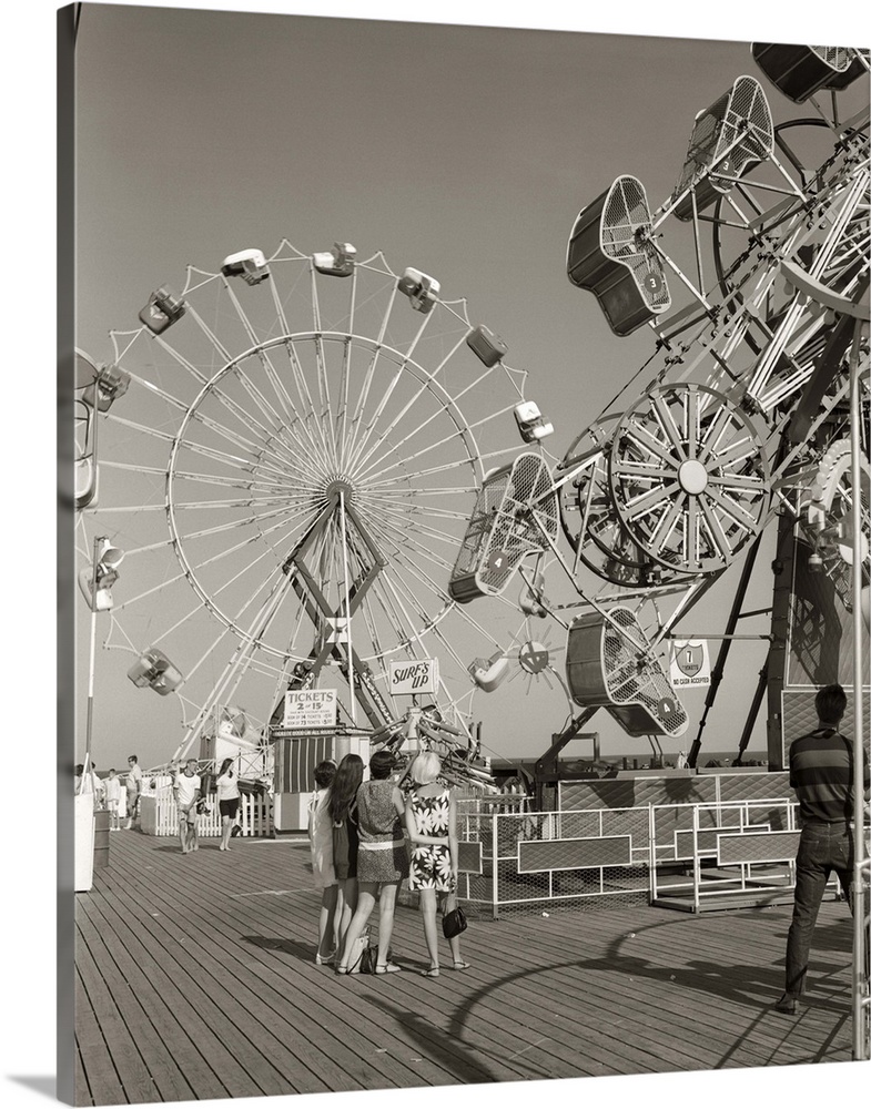 1960's Group Of Teens Looking At Amusement Rides On Pier.