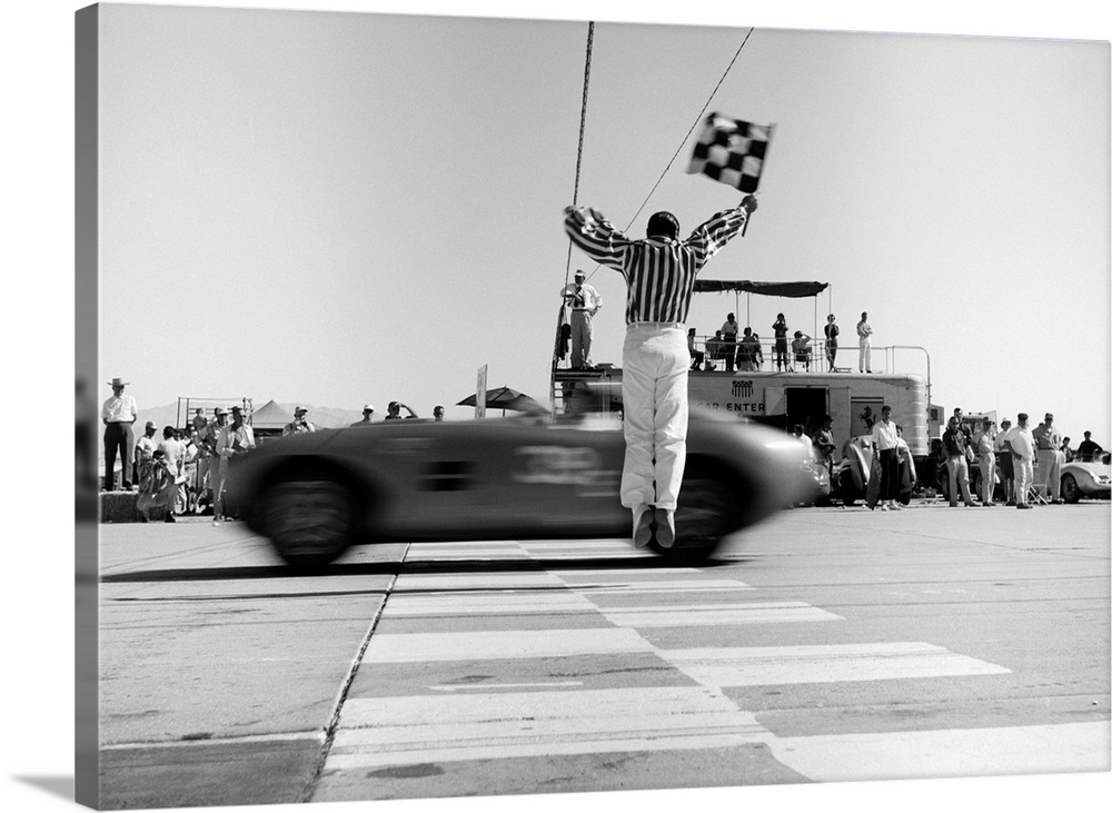 1960's Man Jumping Waving Checkered Flag For Winning Sports Car Crossing The Finish Line.