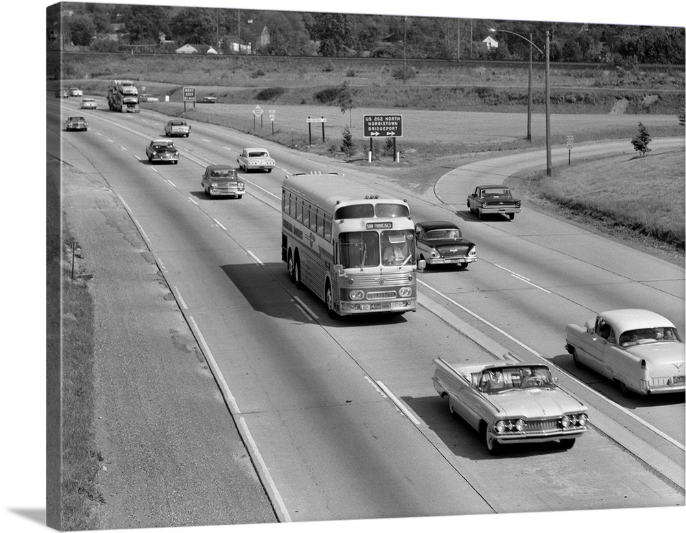 1960's Overhead Of Busy Four Lane Undivided Highway With Convertible Car And Long Haul Passenger Bus Approaching Camera.