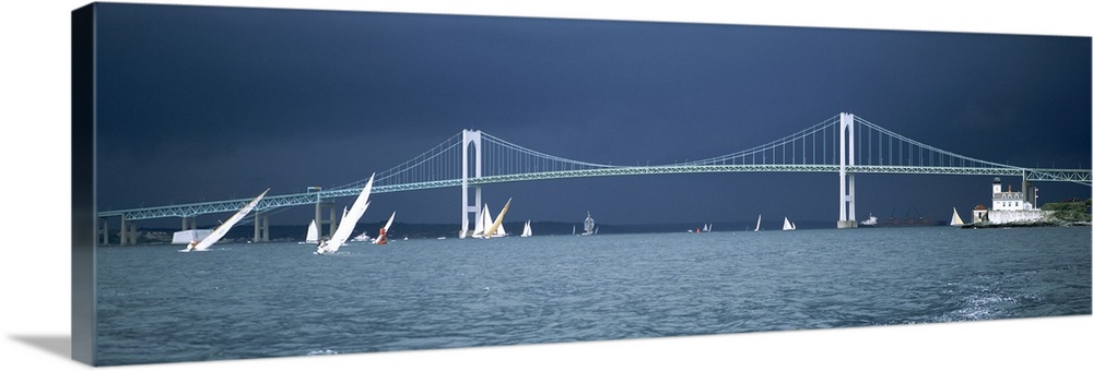 Stark white suspension bridge and boats on the water contrasted against a darkening sky, sailing away from the oncoming sq...