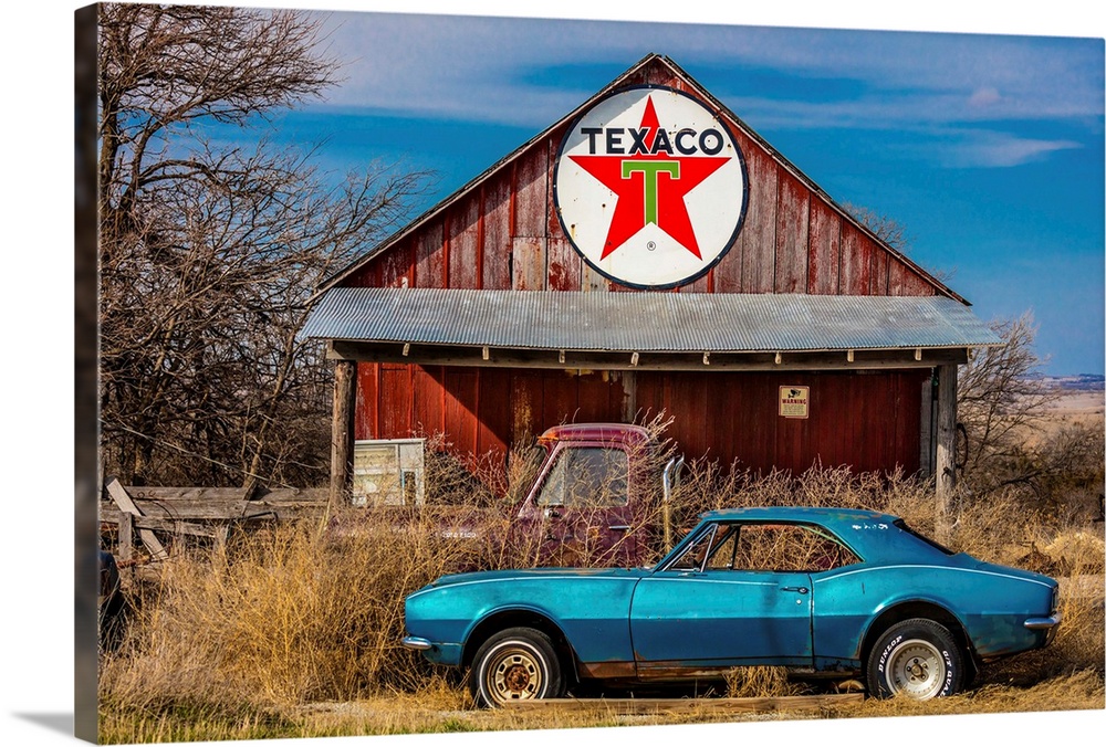Abandoned blue camaro chevrolet in front of deserted texaco station, remote part of nebraska.