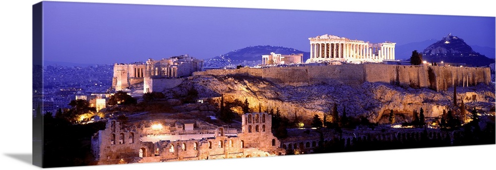 Panoramic image of Acropolis lit up at dusk as it sits high on a hill overlooking Athens, Greece.