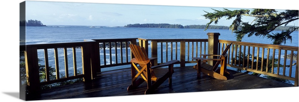 Two chairs sit on a raised deck overlooking a large body of water.